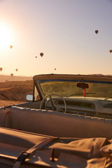 red retro cabriolet with leather inside on the background of blue sky with balloons over sand hills