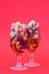Fruit salad in glasses isolated on vivid red background
