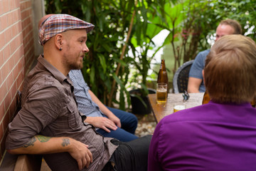 Fototapeta premium Hispter man sitting outdoors with friends while drinking beer