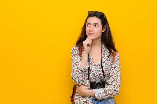 Young brunette traveler woman looking sideways with doubtful and skeptical expression.