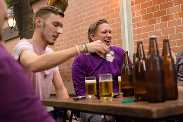 Group of men outdoors sitting and drinking beer