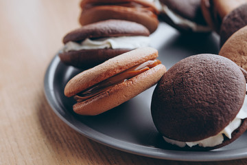 Close up Traditional chocolate and Pumpkin Whoopie pies filled made with vanilla cream cheese in cozy cafe background