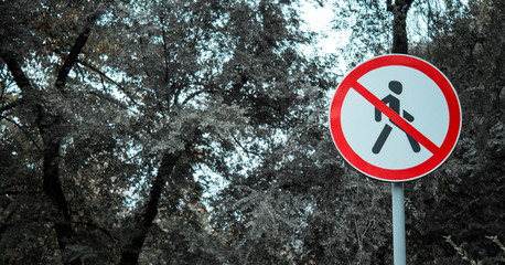 prohibition sign white with red on a background of leaves. prohibiting pedestrian sign. no passage.