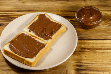 Two slices of bread with delicious chocolate hazelnut spread on wooden table