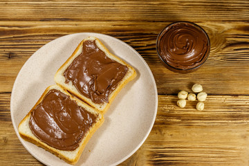 Two slices of bread with delicious chocolate hazelnut spread on wooden table. Top view