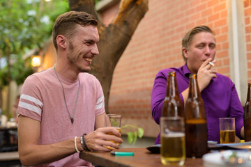 Happy man smiling and laughing while having beer with friends