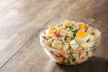 Traditional Russian salad in bowl. Olivier salad on wooden table. Copy space