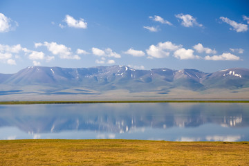Song Kol lake in Kyrgyzstan with mountains reflection in water.