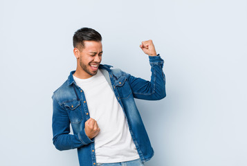 Young handsome filipino man raising fist after a victory, winner concept.