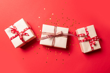 Creative composition with red present box, ribbons holiday decorations on red background. Creative composition for birthday, Christmas, New Year