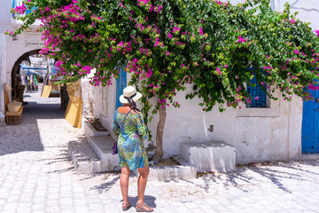 Tunisia. (Southern Tunisia). Island of Djerba. Houmt Souk. A woman front of flowering bougainvillea...