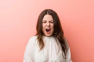 Young caucasian curvy woman standing against pink background