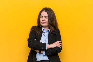 Young plus size caucasian business woman frowning face in displeasure, keeps arms folded.