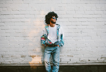 Stylish young man in a retro jacket. Fashion trends of 90s. Handsome hipster guy with beard with curly hair.