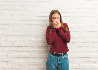 Young cool woman over a bricks wall laughing about something, covering mouth with hands