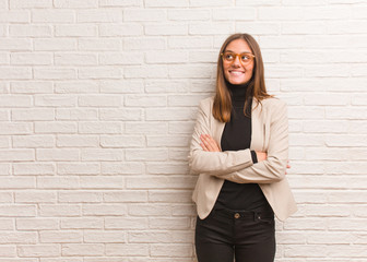 Young pretty business entrepreneur woman smiling confident and crossing arms, looking up