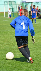 Obraz premium Young goalkeeper kicks the ball out