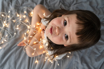 Little girl is playing with New Year's garlands. A child among the New Year's lights