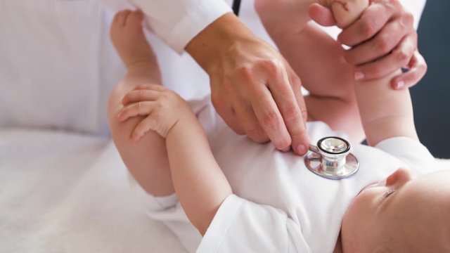 medicine, healthcare and pediatrics concept - female doctor with stethoscope listening to baby girl's patient heartbeat or breath at clinic or hospital