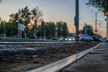 Fototapeta premium Tram tracks, rails close-up against a blurred city, cars during sunset