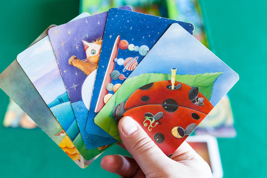 MOSCOW, RUSSIA - APRIL 3, 2019: player shows picture cards during Dixit board game . Dixit is a card game created by Jean-Louis Roubira and first published by Libellud in 2008