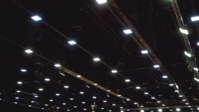 The metal ceiling of a large pavilion with a large number of lighting fixtures and a ventilation system. 