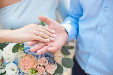 Groom wears bride a wedding ring Bride hand holds a beautiful wedding bouquet