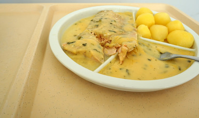 Salmon with boiled potatoes and gravy served as a delicious lunch on the tray