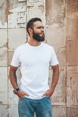 Handsome hipster man with beard wearing white blank t-shirt with space for your logo or design....