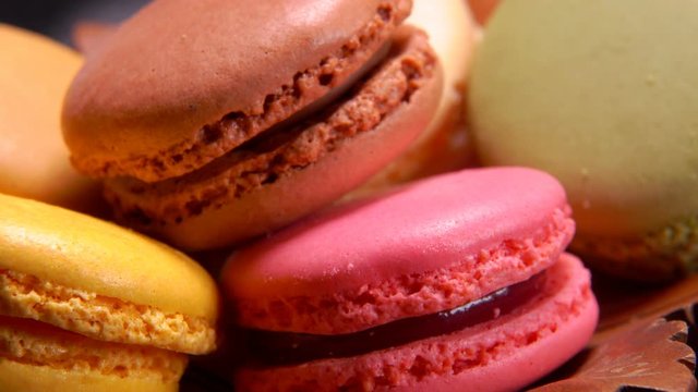 Close-up of multi-colored French macaroons lie on a brown plate