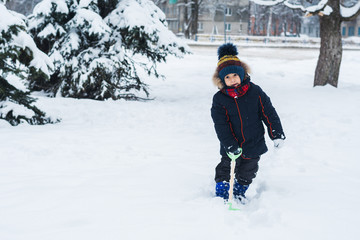 Fototapeta na wymiar boy with a shovel playing outside in the snow