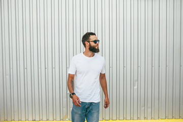 Handsome hipster man with beard wearing white blank t-shirt with space for your logo or design....