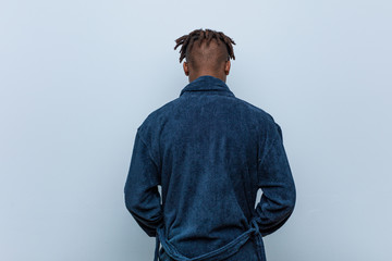 Young african black man wearing pajama from behind, looking back.