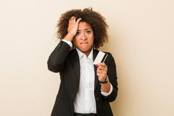 Young african american woman holding a credit card being shocked, she has remembered important...