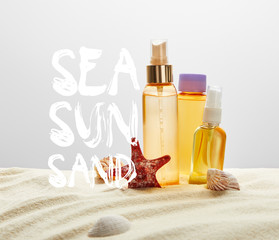 bottles with sunscreen products on sand with starfish on grey background with sea, sun, sand lettering