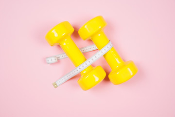 Flat lay shot of dumbbells on pink background.