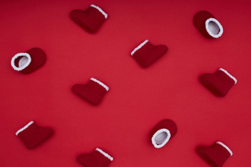 Pattern with red crochet Santa boots on the red. Christmas concept