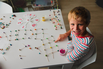 boy making letters, geometric shapes from sticks and clay, engineering and STEM