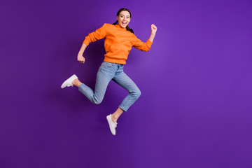 Fototapeta na wymiar Full body photo of positive cheerful youth girl jump run after discounts feel content wear sportswear denim jeans white sneakers isolated over violet purple color background