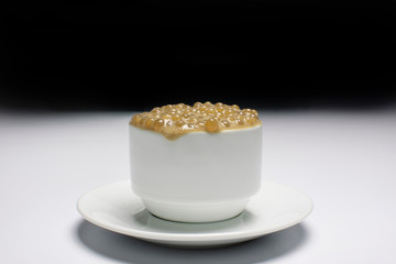 Brazilian dessert made of tapioca pearls called sagu in coffee flavor in a white cup and background