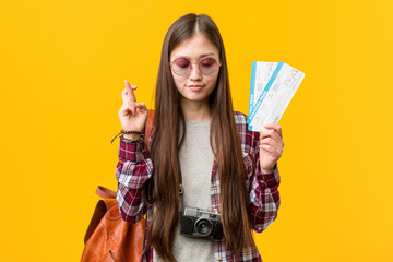Young asian woman holding an air tickets crossing fingers for having luck