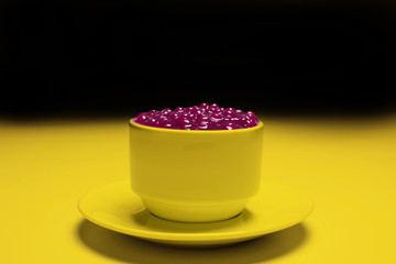 Brazilian dessert made of tapioca pearls called sagu in red wine flavor in a yellow cup and background
