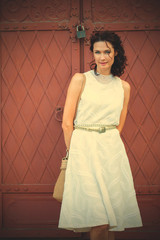 Fototapeta premium woman in a white dress near the old metal gate