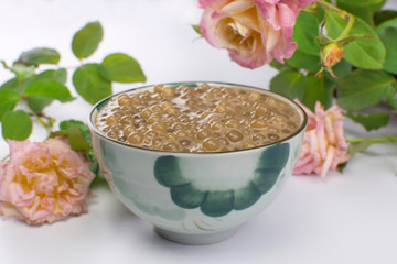Brazilian dessert made of tapioca pearls called sagu in coffee flavor in a bowl with roses in the background