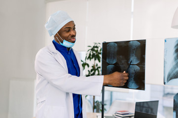 Portrait of young African male doctor surgeon or radiologist looking at a radiography