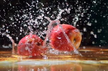 Juicy red apples in water. Apples fall into the water, drops. Useful food snacks.