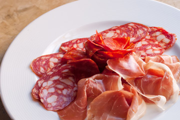 Lunch meats cold cuts. Sliced Jamon chorizo smoked sausages white plate. Traditional cold snacks mediterranean delicatessen