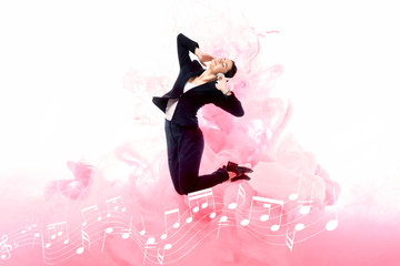 young businesswoman listening music in headphones while jumping on background with music notes and pink smoke splashes isolated on white