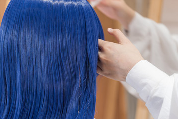 青い髪を施術する美容師