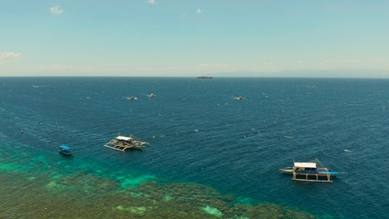 Aerial view of Diving boats return from diving off the island of Pescador. Filipino boats floating on top of clear blue waters.